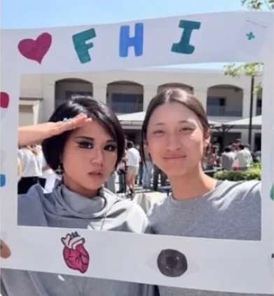 Students posing behind FHI's hand-decorated photo frame at a school fair