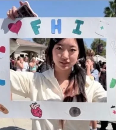 Students posing behind FHI's hand-decorated photo frame at a school fair