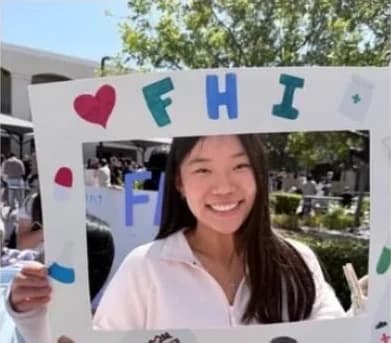 Students posing behind FHI's hand-decorated photo frame at a school fair