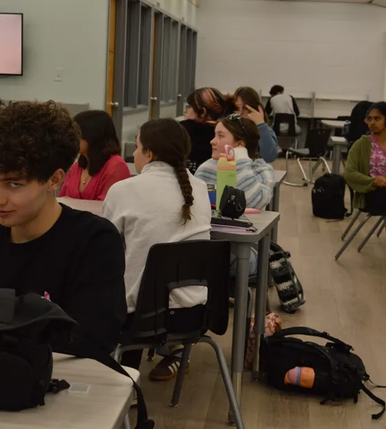 Students at tables during the breast cancer awareness presentation