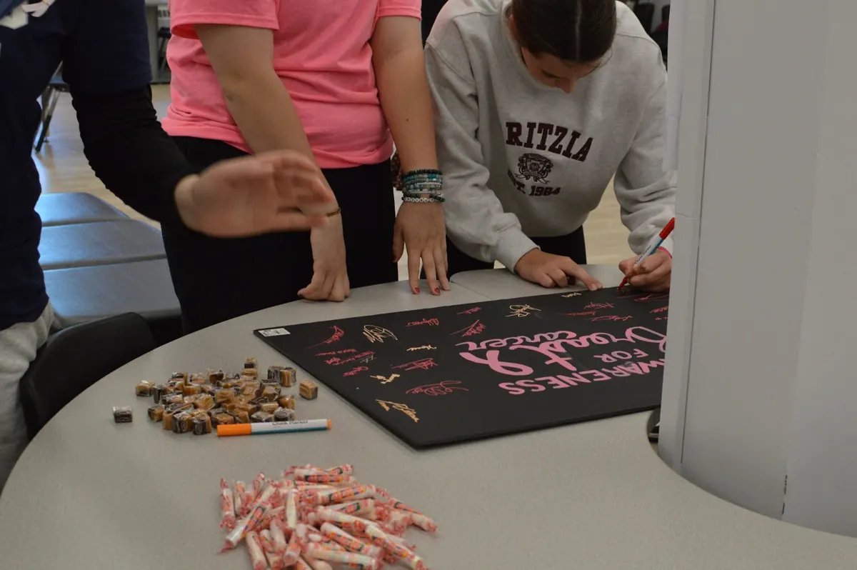Students leaning over the awareness poster to add their names