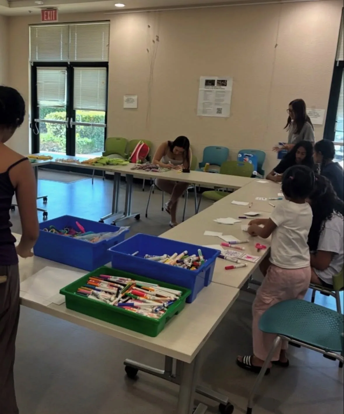 Volunteers and children at long tables with tubs of markers, making cards